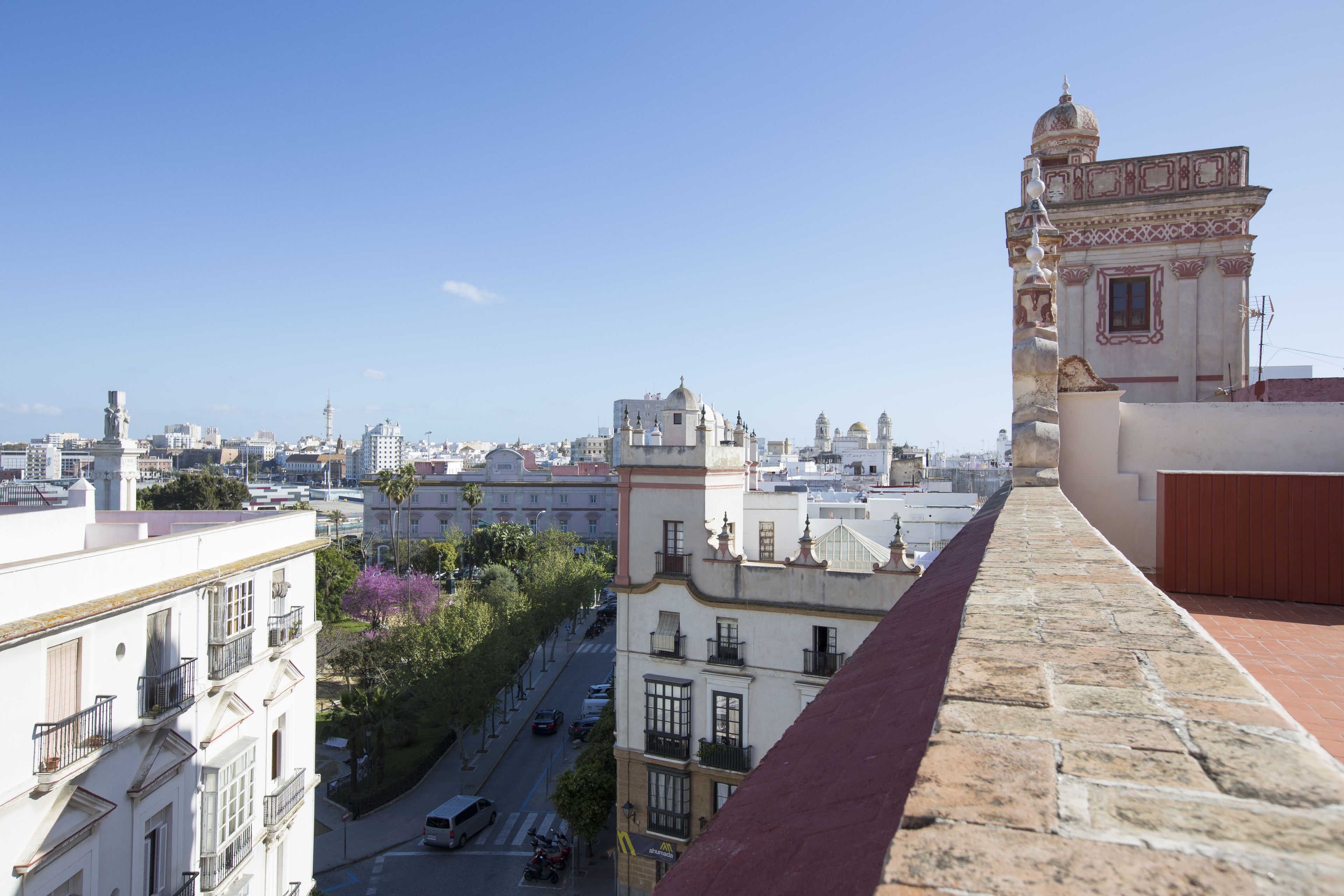Un paisaje urbano con una imponente torre de iglesia y una calle con coches estacionados.
