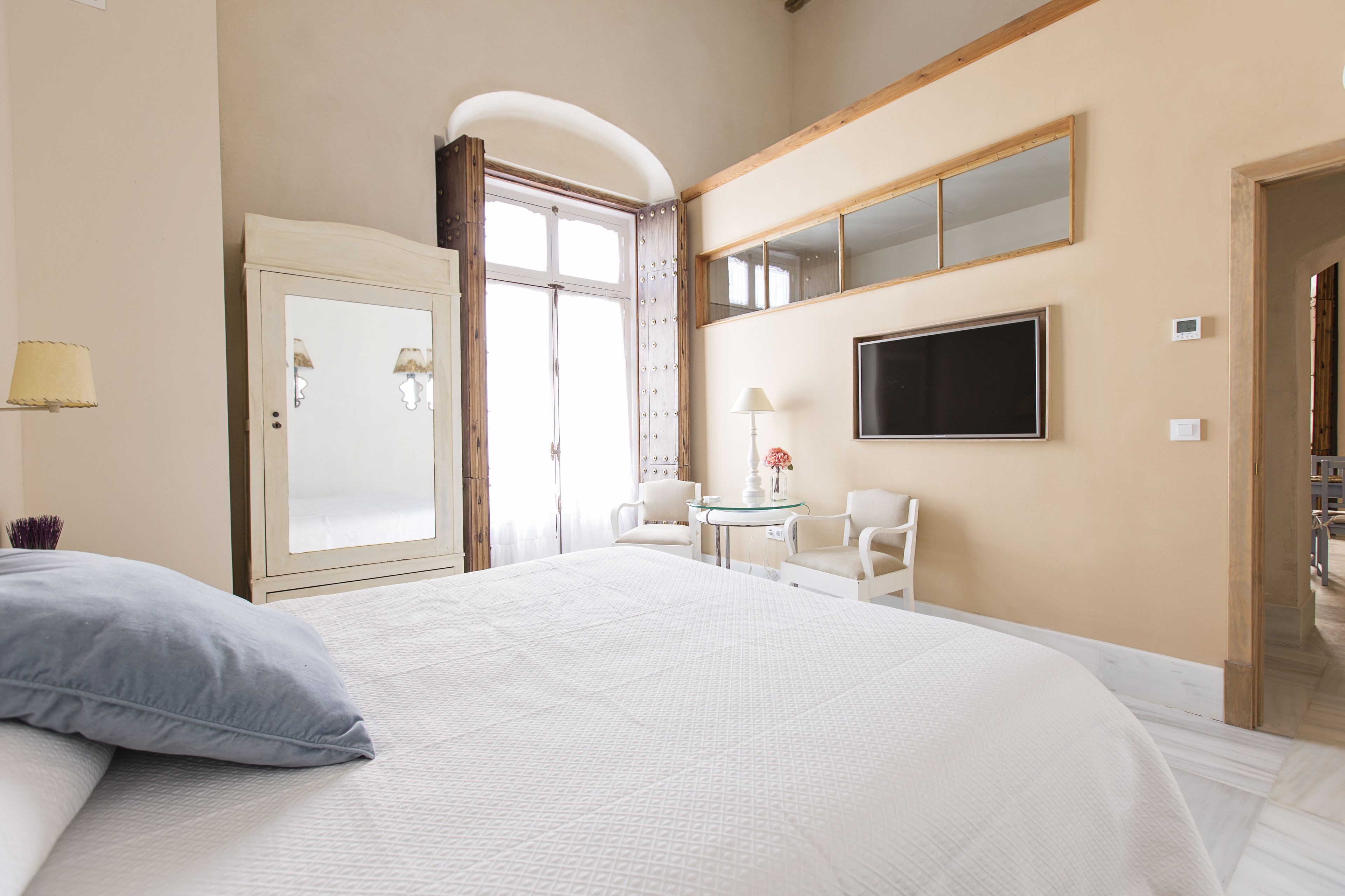 Una habitación de hotel con una cama grande, un escritorio con dos sillas, un televisor y un armario.