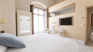 Una habitación de hotel con una cama grande, un escritorio con dos sillas, un televisor y un armario.