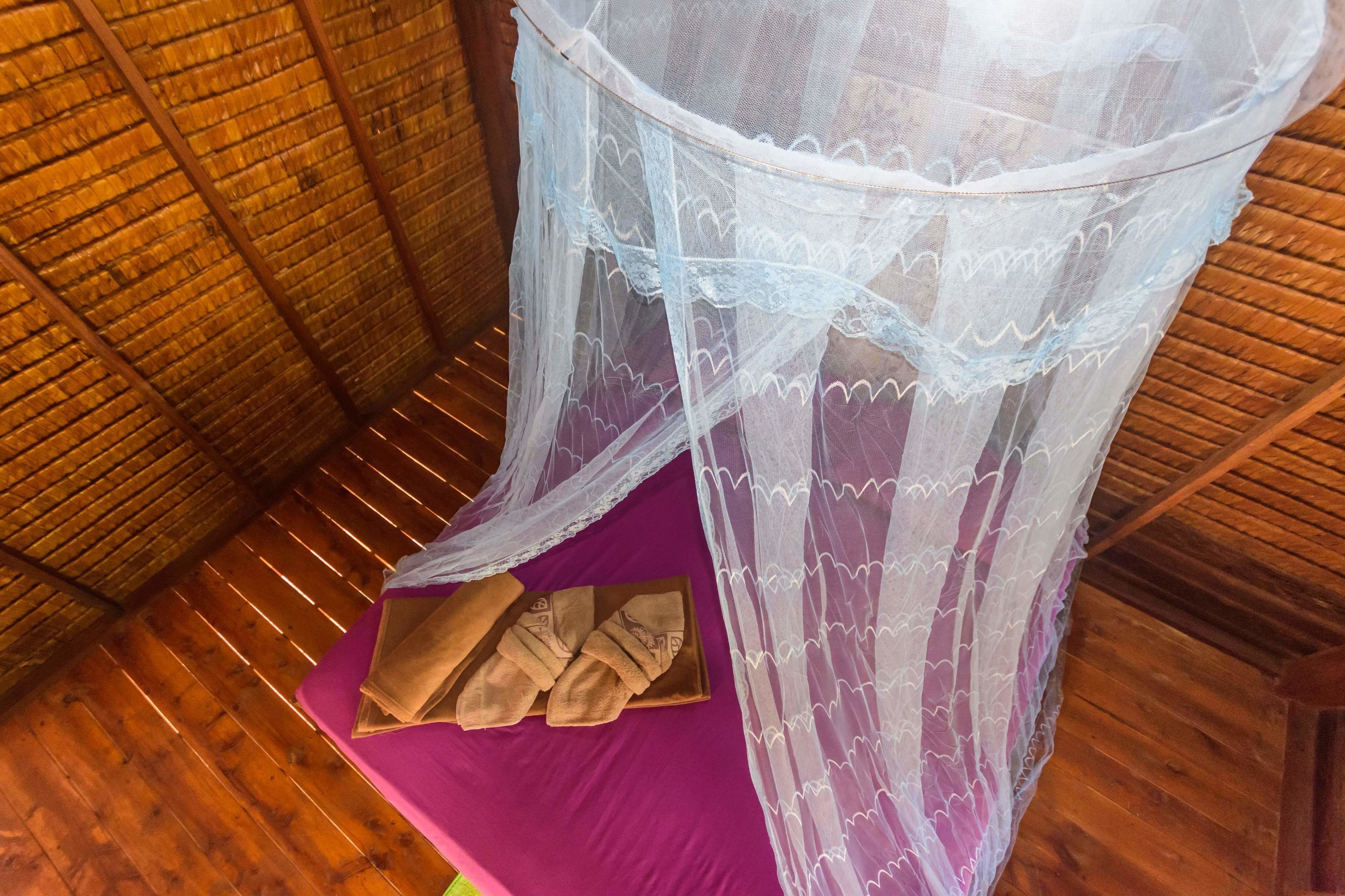 Una habitación de madera con una cama morada y un mosquitero.