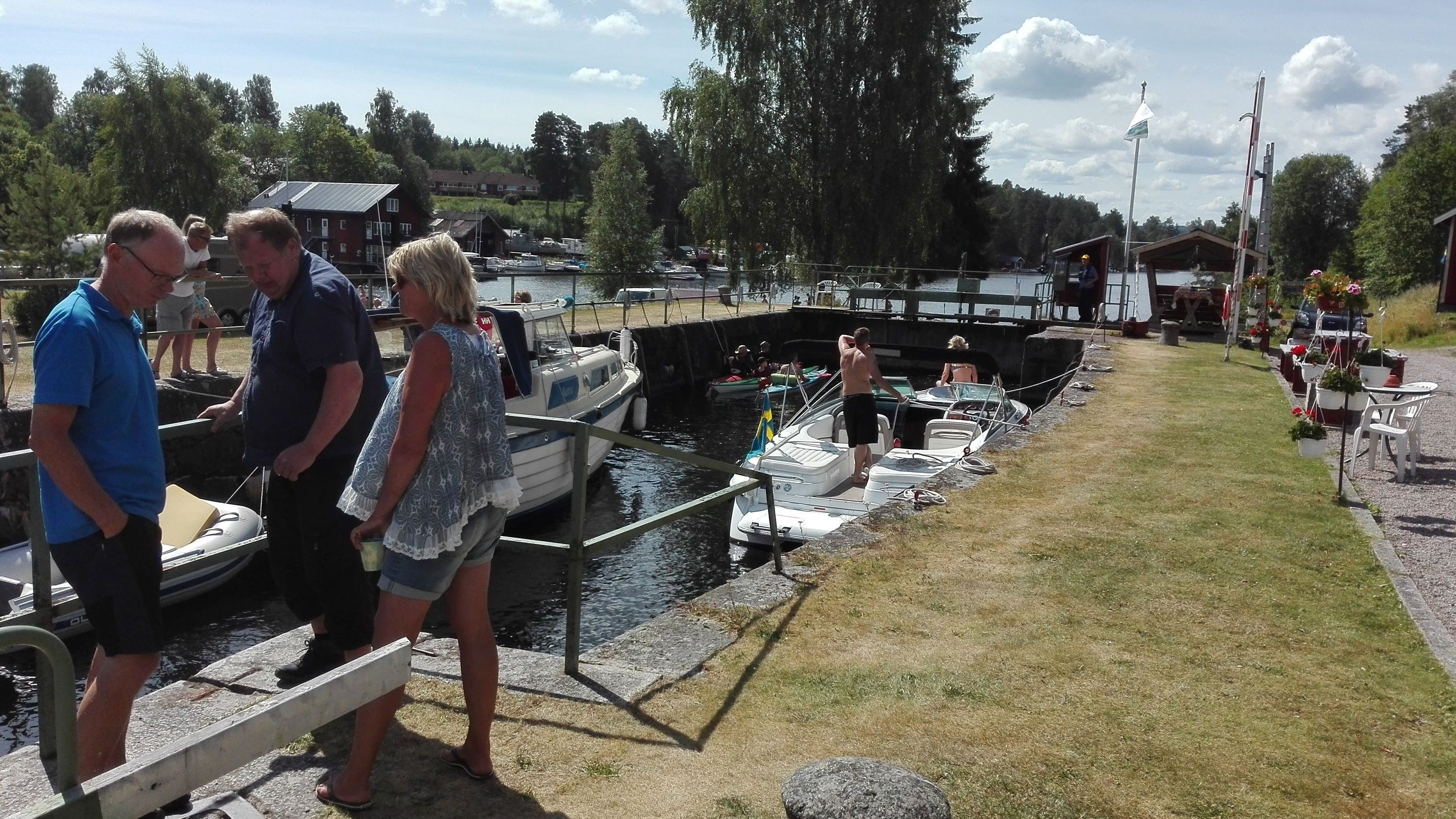 A narrow waterway with boats docked on both sides, a pedestrian walkway, and a small building with a flag.