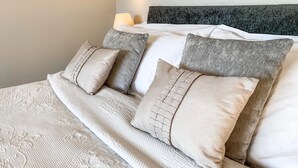 Cama bem arrumada com colcha estampada e várias almofadas.