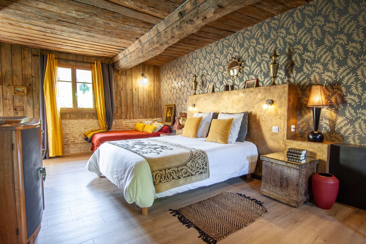 Een houten kamer met een bed, een nachtkastje en een rode vaas.