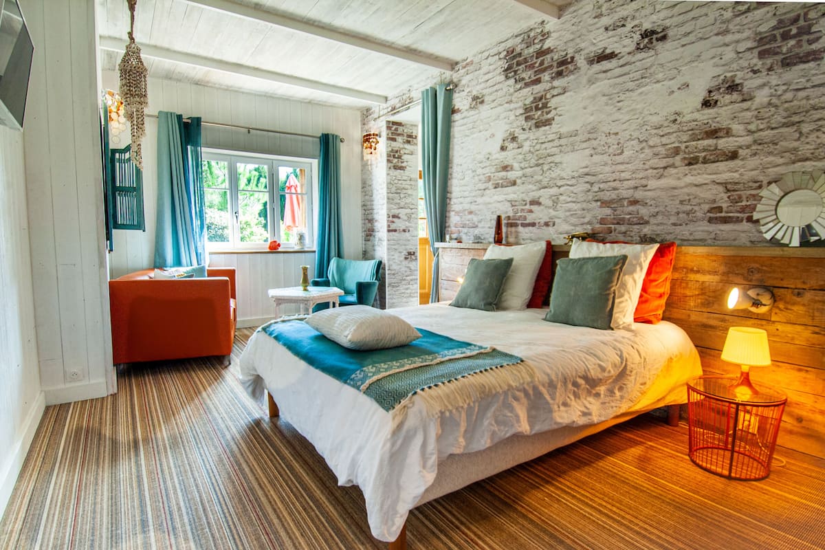 Een slaapkamer met een bed, een stoel, een klein tafeltje en een lamp.