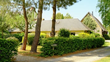 A building with a sloped roof, surrounded by dense greenery and trees.