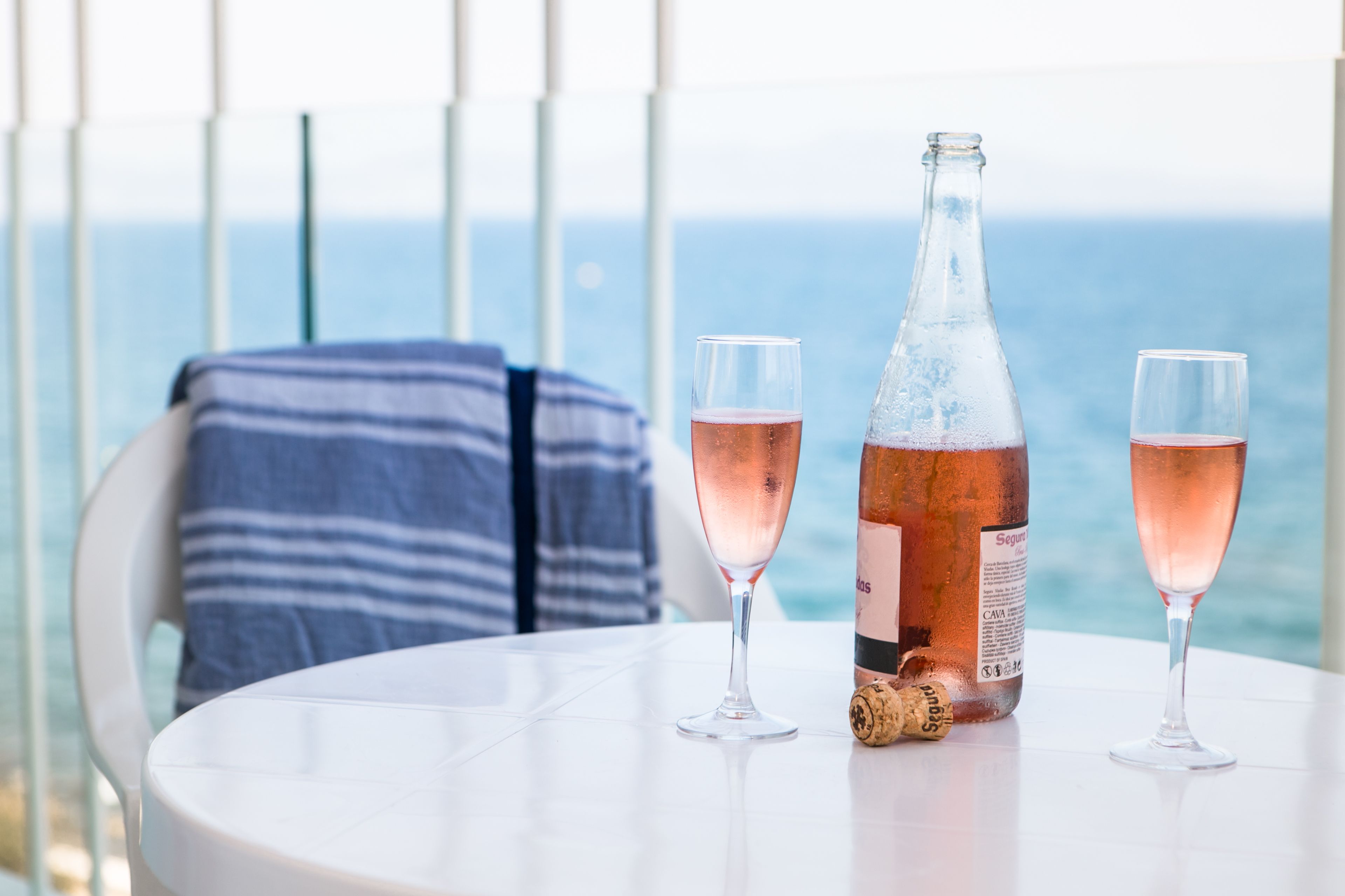 A table with two glasses of rosé wine, a bottle, and a cork.