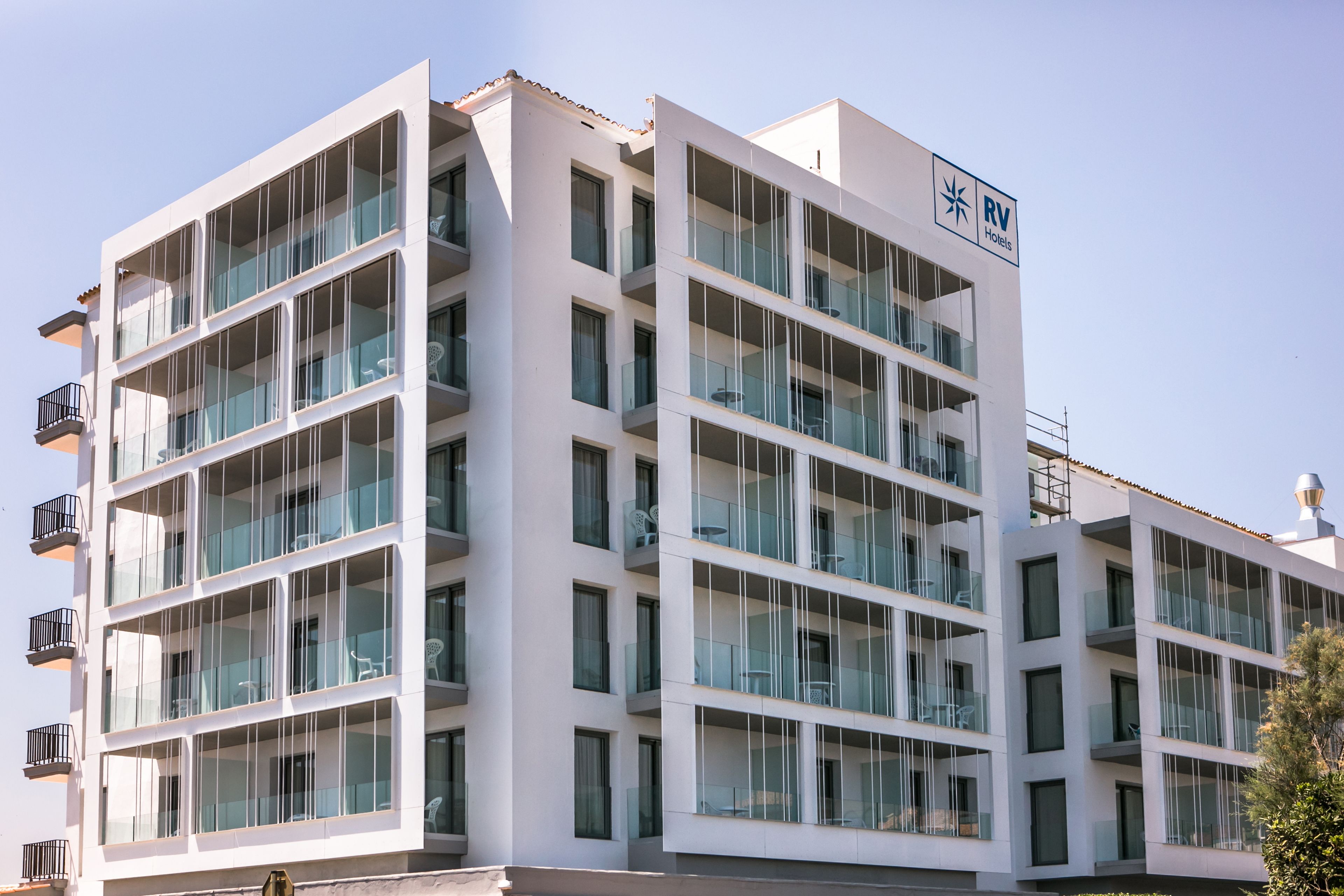 A multi-story hotel with a modern design, featuring balconies and large windows.