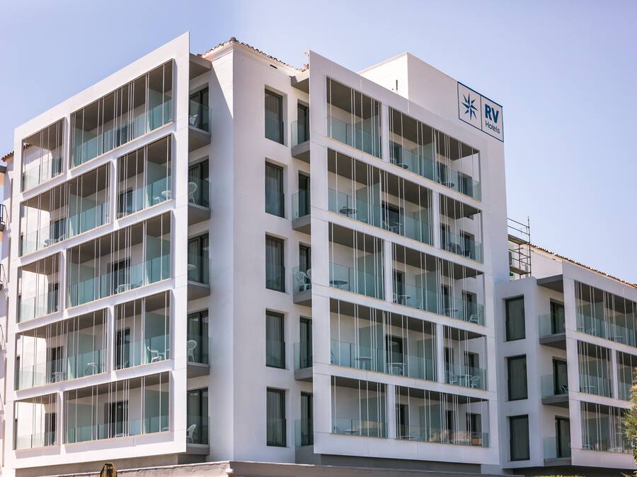 Un hotel de varios pisos con diseño moderno, con balcones y ventanas amplias.