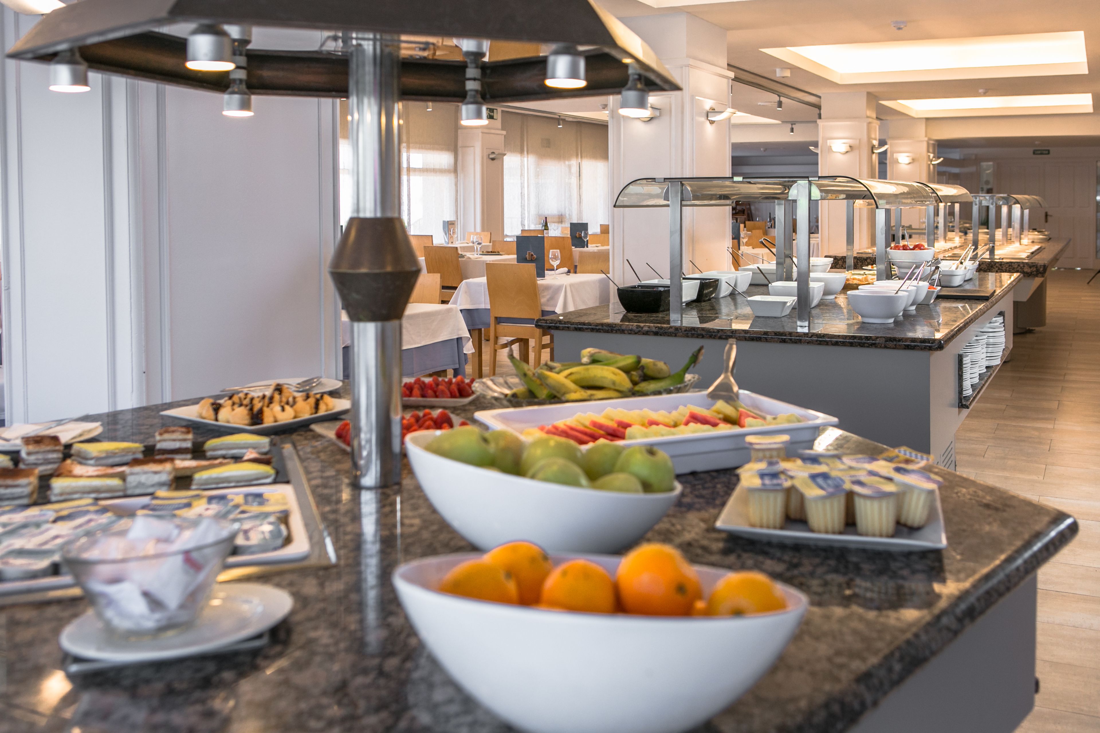A buffet with various food items and a fruit bowl.
