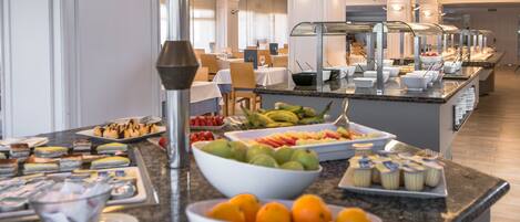 A buffet with various food items and a fruit bowl.
