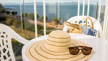 Ein weißer Tisch mit einem Strohhut und Sonnenbrille, der einen schönen Blick auf das Meer und die entfernte Landschaft bietet.