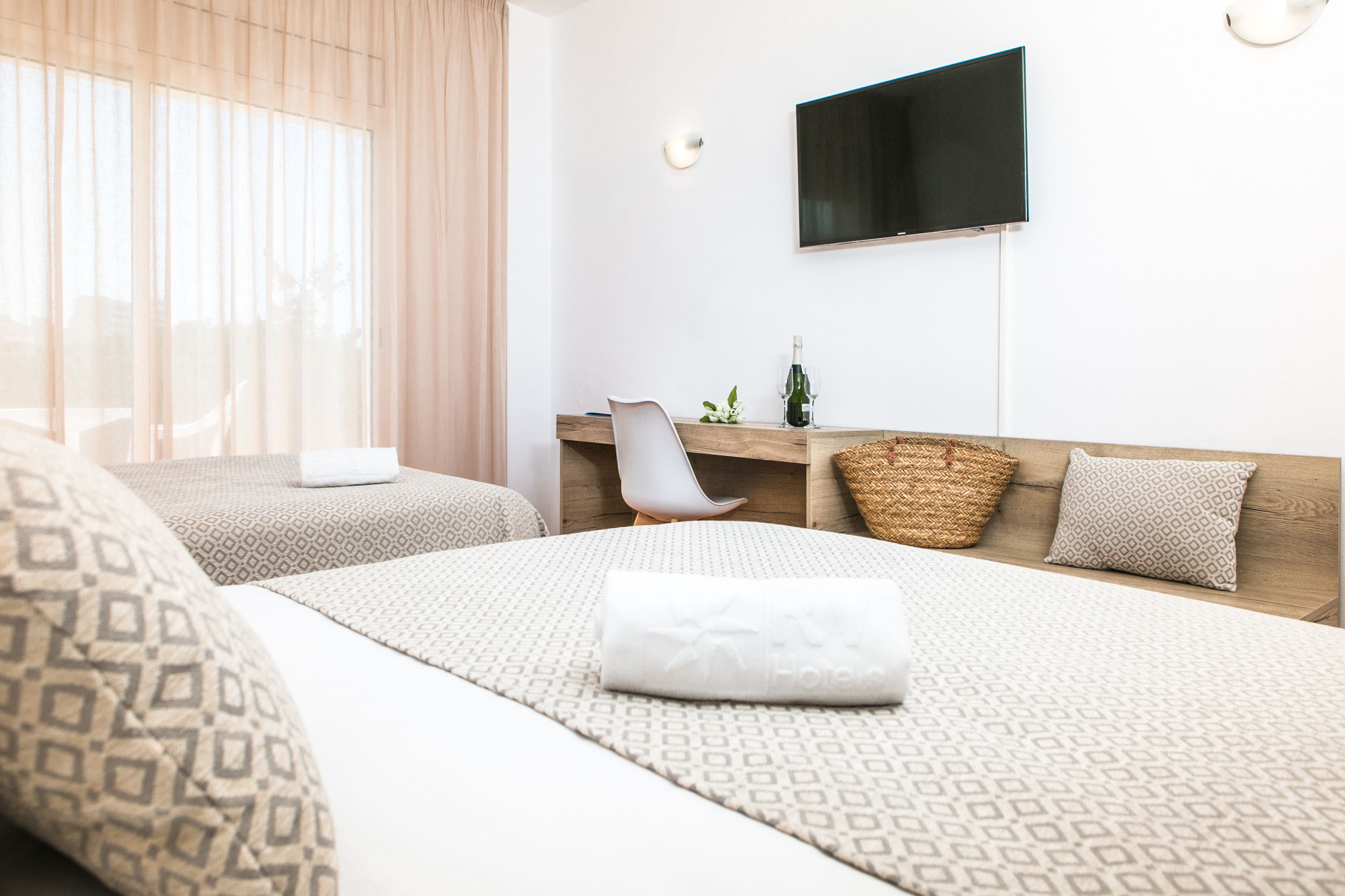 A hotel room with two beds, a TV, a desk, and a chair.