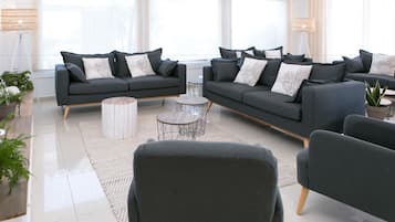 A modern living room with a grey sofa set, a round coffee table, and a potted plant.