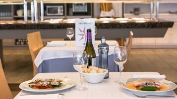 A dining table set with plates of food, wine glasses, and a bottle of wine.