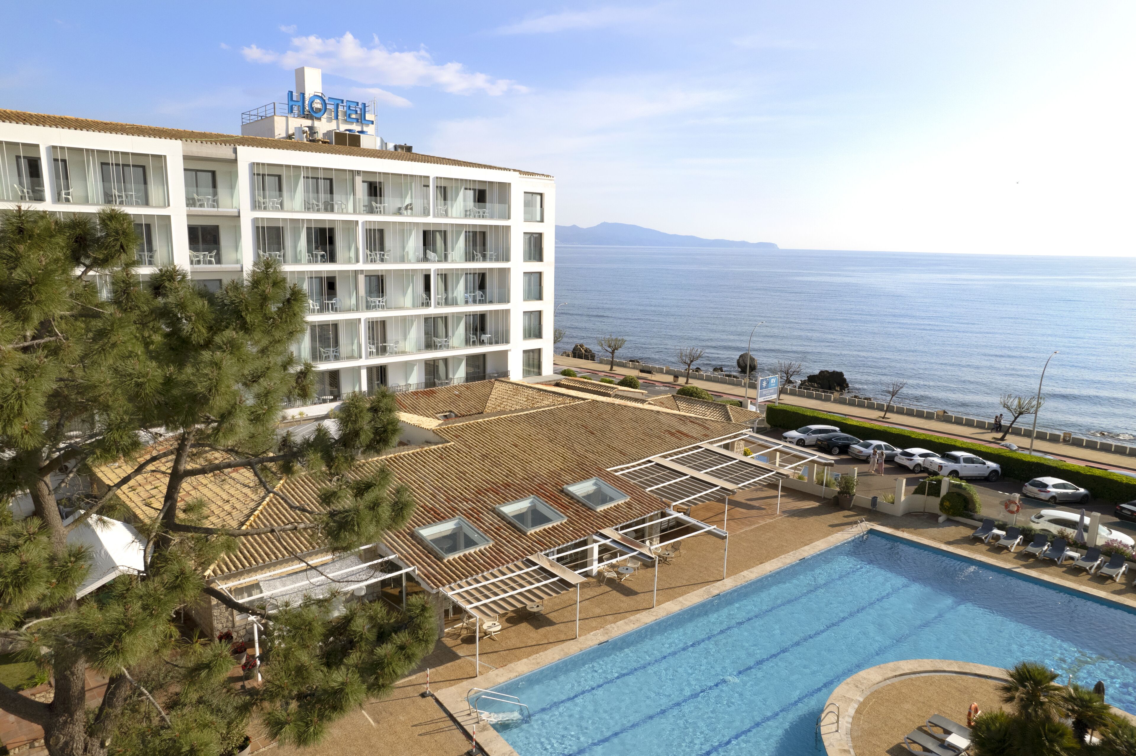 Ett hotell med en pool, utsikt över havet och en byggnad med flera våningar och balkonger.