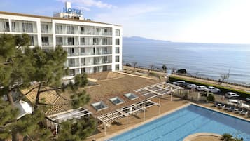 Ett hotell med en pool, utsikt över havet och en byggnad med flera våningar och balkonger.