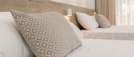 Una cama bien hecha con almohadas estampadas y un cabecero de madera.