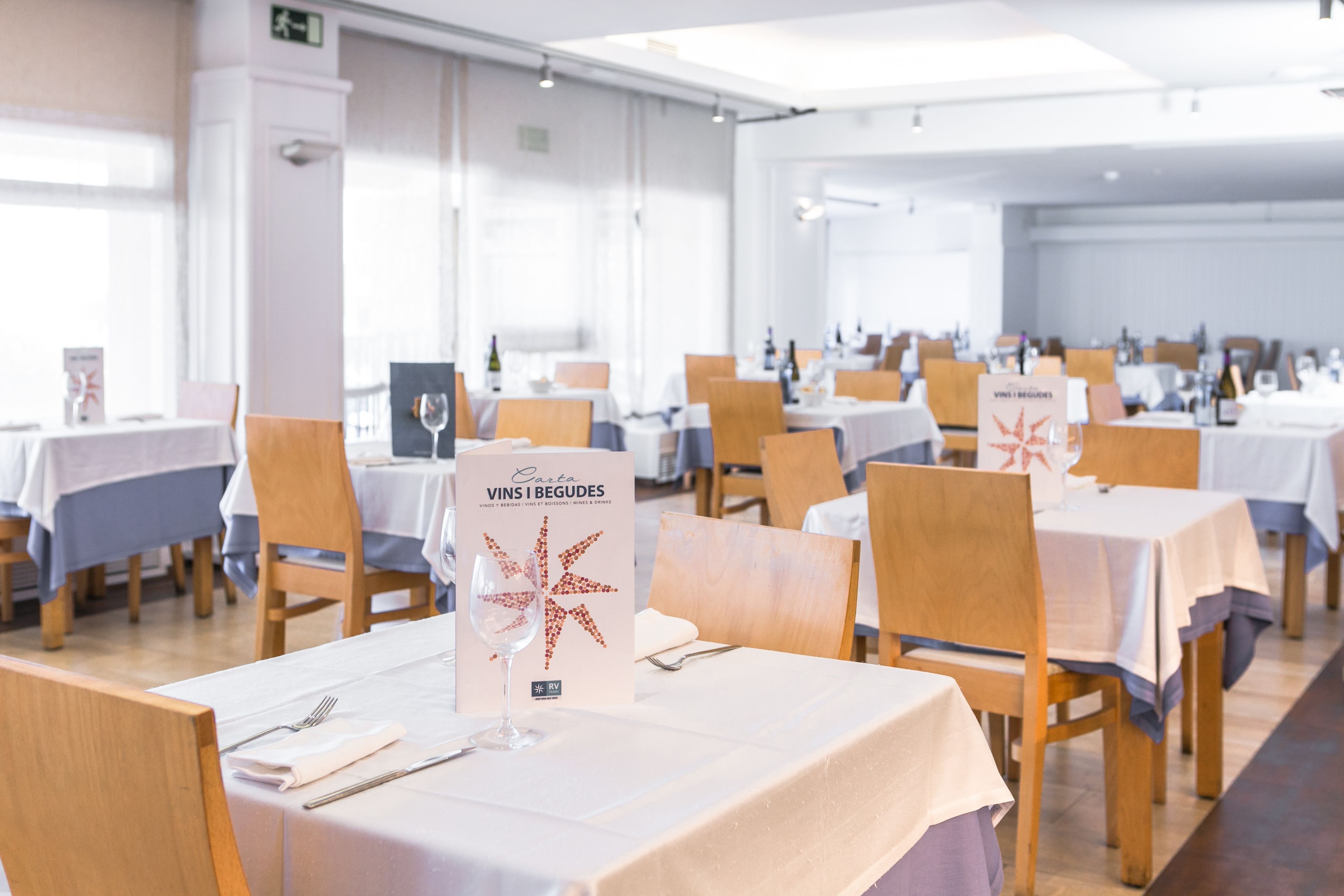 Un comedor con mesas dispuestas para el servicio, un atril para el menú y un interior limpio y moderno.