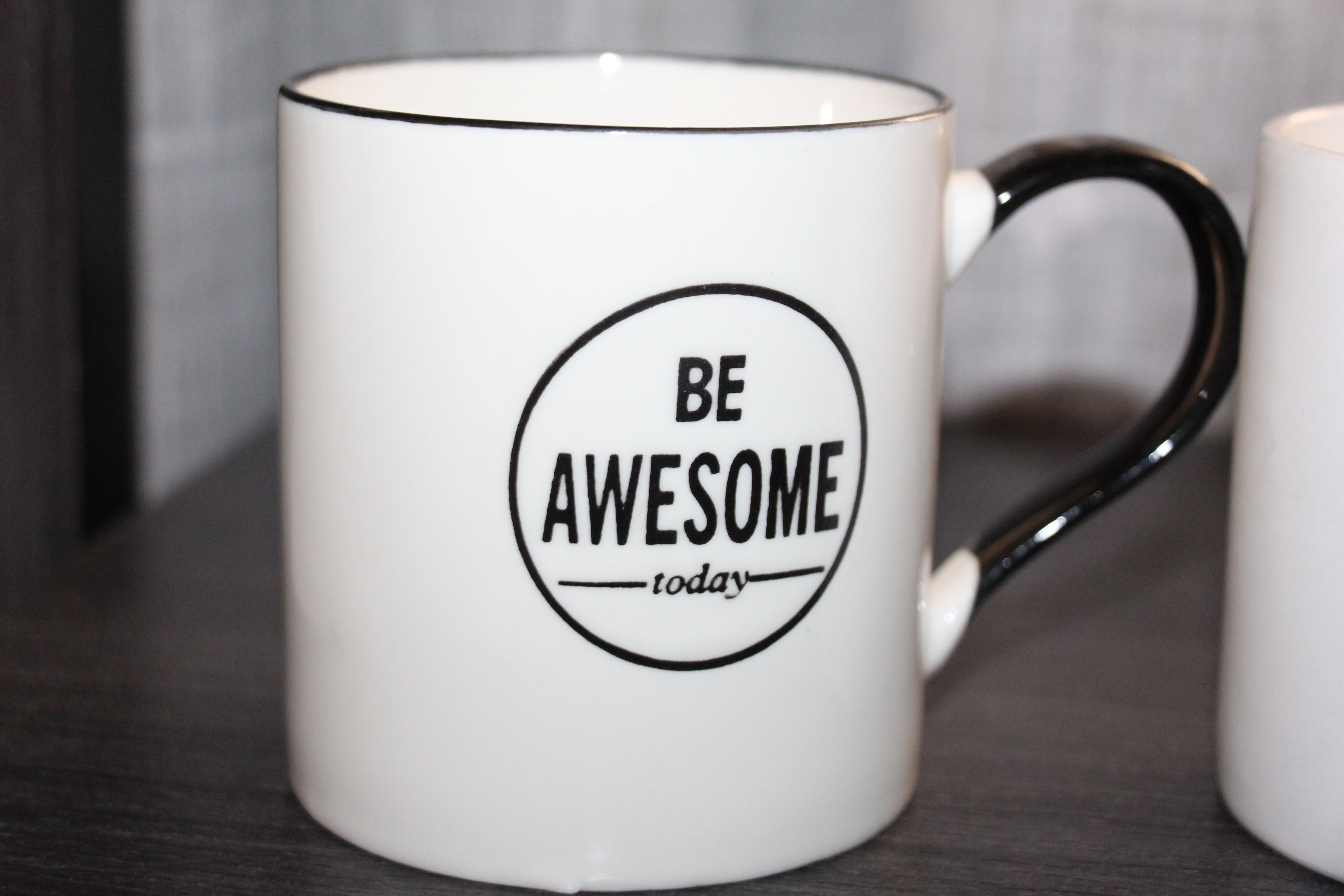 A white mug with a black handle and a motivational quote "BE AWESOME today" printed on it.