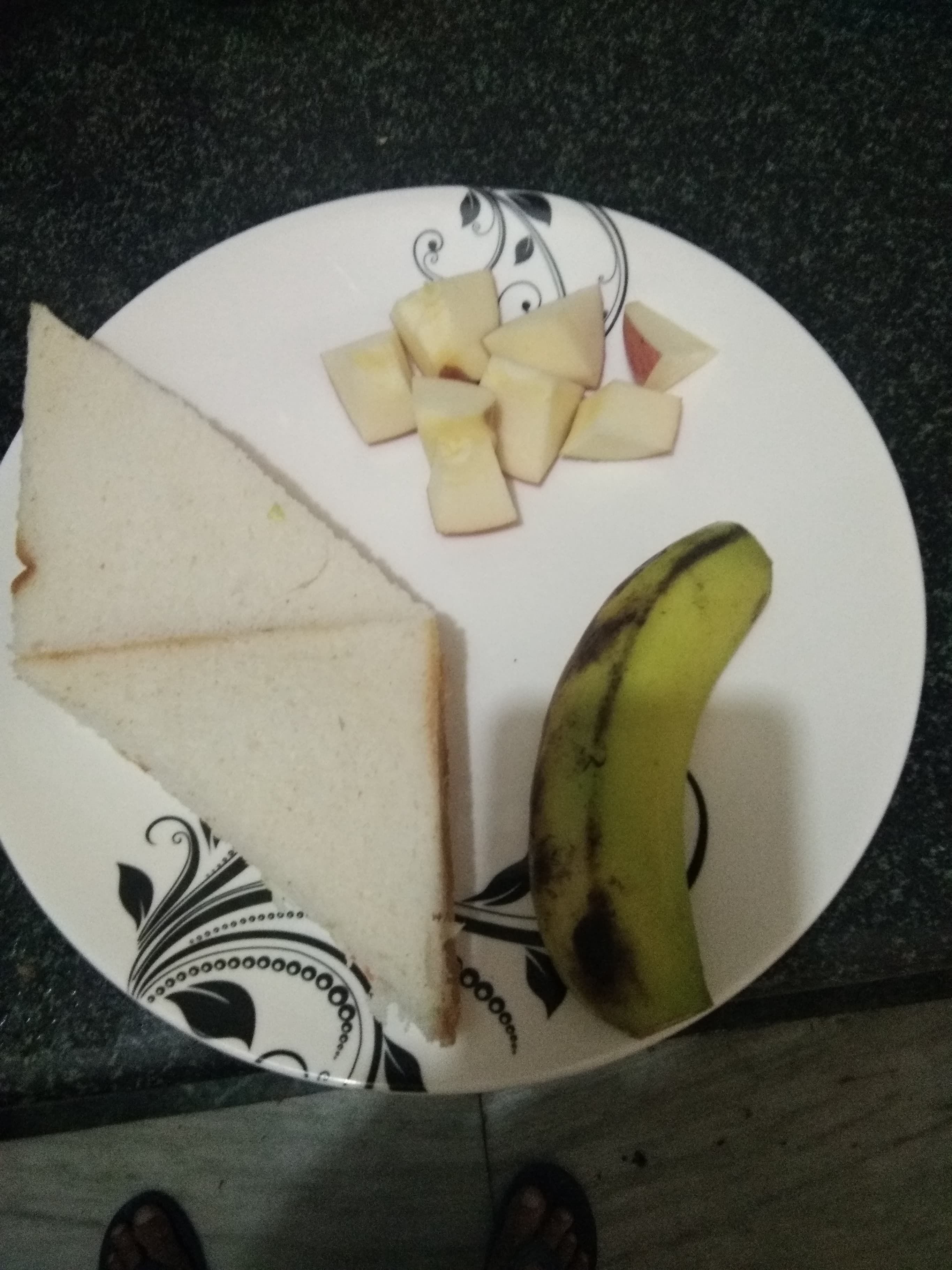 A plate with slices of bread, pieces of fruit, and a banana on a patterned plate.
