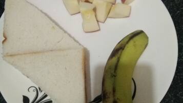 A plate with slices of bread, pieces of fruit, and a banana on a patterned plate.