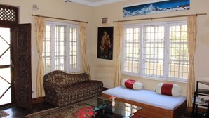 Una habitación con sofá, cama, una mesita de centro de vidrio y un cuadro en la pared.