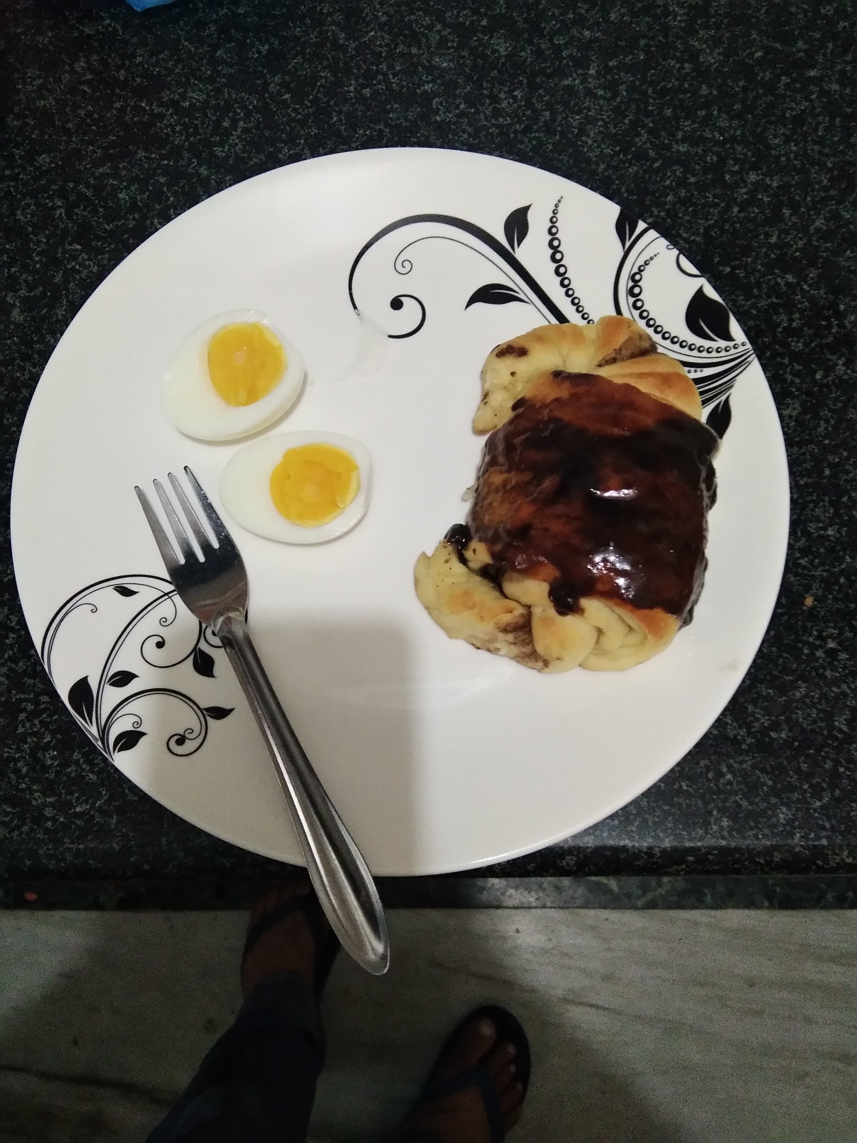 Un plato con un guiso al horno, dos huevos cocidos y un tenedor sobre un plato estampado.