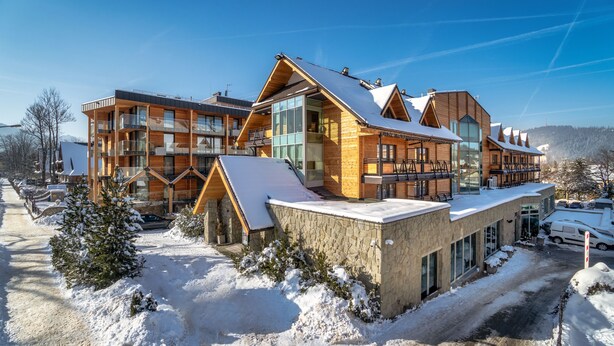 A modern multi-story hotel with a wooden exterior, large windows, and a snow-covered roof. - Hotel Wersal (Zakopane)