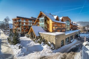 A modern multi-story hotel with a wooden exterior, large windows, and a snow-covered roof. - Hotel Wersal (Zakopane)