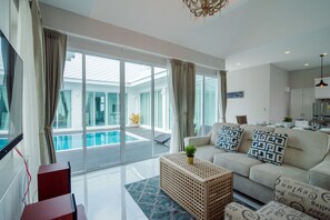 Un salon moderne avec un canapé, une table basse et une vue sur une piscine.