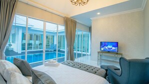 A hotel room with a large bed, a TV, a view of a swimming pool, and a balcony. - Baan Marwin Hua Hin (Hua Hin)