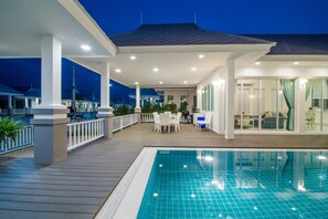 Un espace piscine couvert doté d’une terrasse, de chaises longues et d’un coin salon avec une table et des chaises.