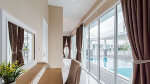 A modern hotel room with a large window, a pool view, and a seating area with a bench and a chair. - Baan Marwin Hua Hin (Hua Hin)