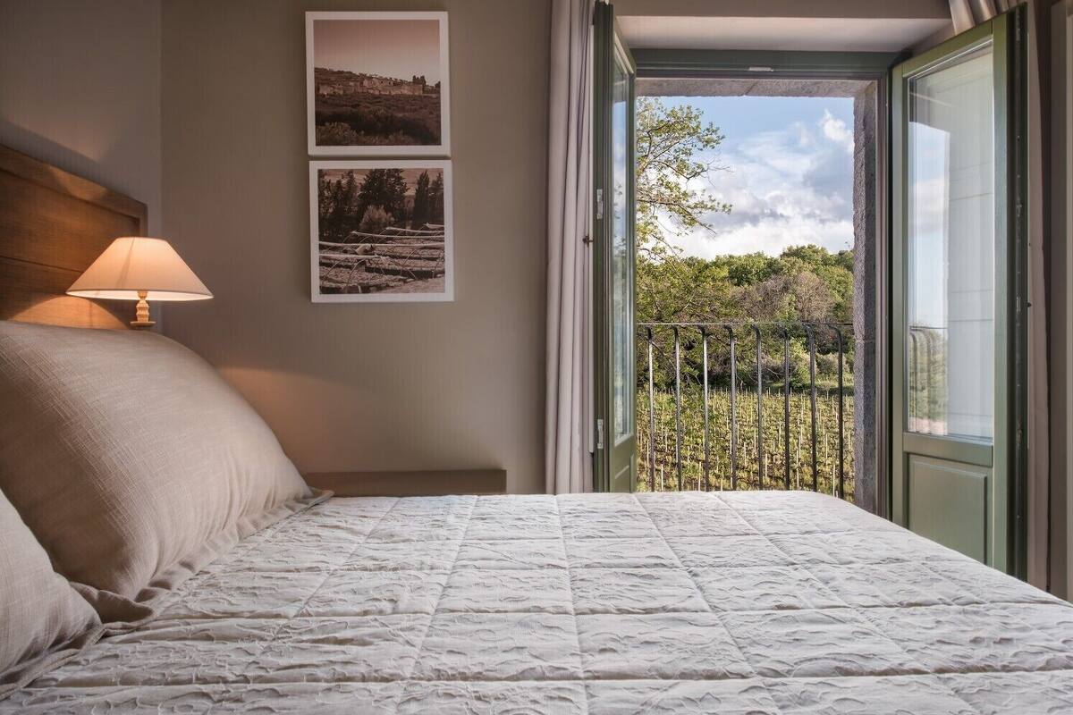 A bedroom with a bed, a nightstand, a lamp, and two framed pictures on the wall.