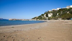 A beach with a rocky outcrop and buildings on a hillside. - Meandros (Apokoronas)