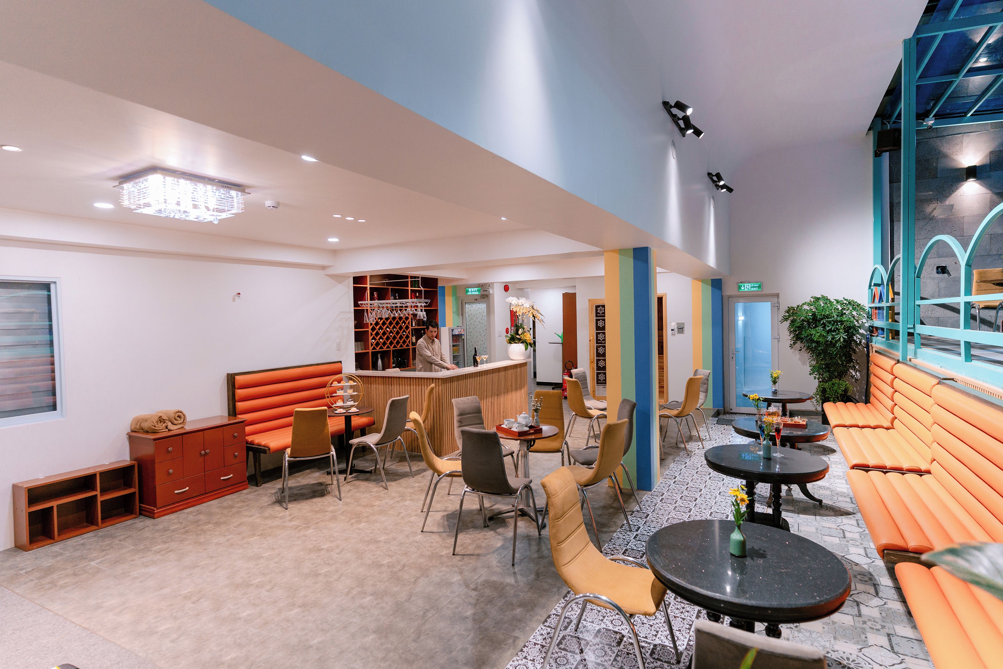 A modern interior with a bar area, seating arrangements, and a staircase leading to an upper level.