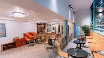 A modern interior with a bar area, seating arrangements, and a staircase leading to an upper level.