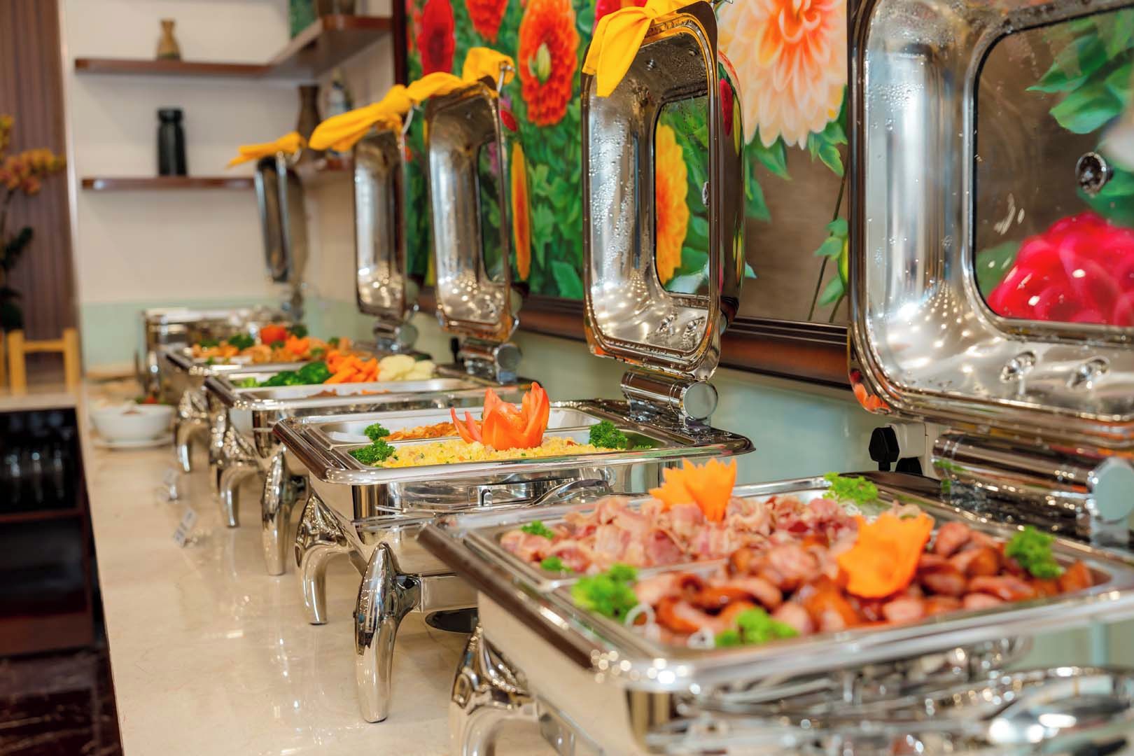 Una barra de buffet con diversos alimentos y una pared decorativa al fondo.