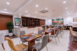 A restaurant with multiple dining tables and chairs, a bar area with shelves of bottles, and a large floral painting on the wall. - DAHLIALAND SAIGON HOTEL & SWIMMING POOL (Ho Chi Minh City)