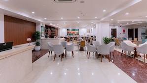 Een moderne hotellobby met een receptiebalie, een zithoek en een groot schilderij aan de muur.