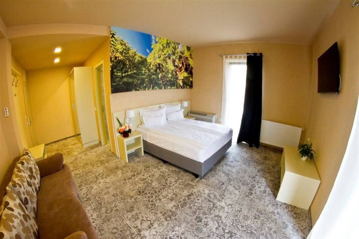 Une chambre à coucher avec un grand lit, un canapé, un tableau au mur et une fenêtre avec des rideaux.