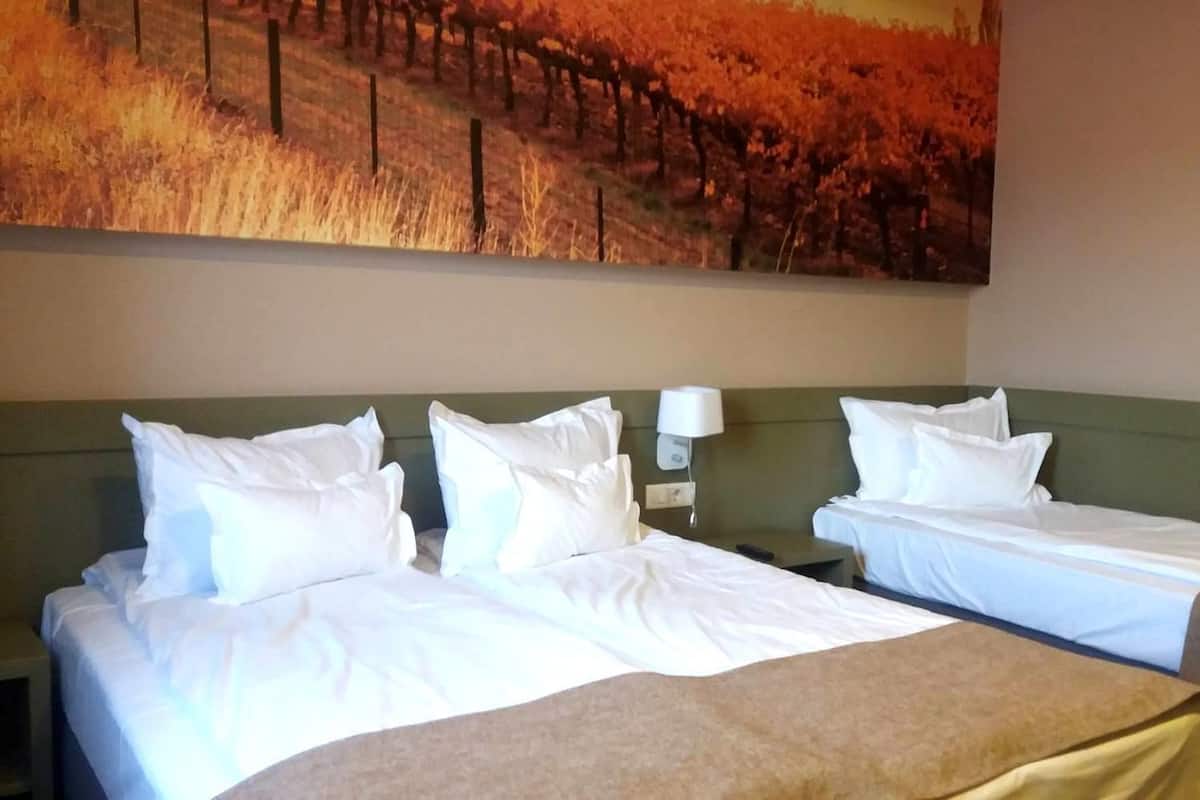 Une chambre d’hôtel avec deux lits, une table de chevet et une lampe fixée au mur.