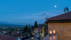 Ein Wohngebiet mit Blick auf eine Stadt in der Ferne, ein Haus mit rotem Ziegeldach und eine brennende Kerze am Balkon.