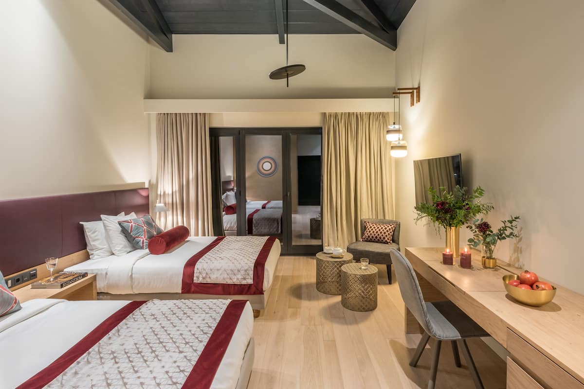 Une chambre d’hôtel moderne équipée de deux lits, d’un bureau et d’un coin salon.