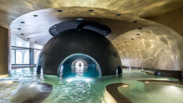 Ein Innenpool mit einer markanten, gewölbten Decke und klarem Wasser.