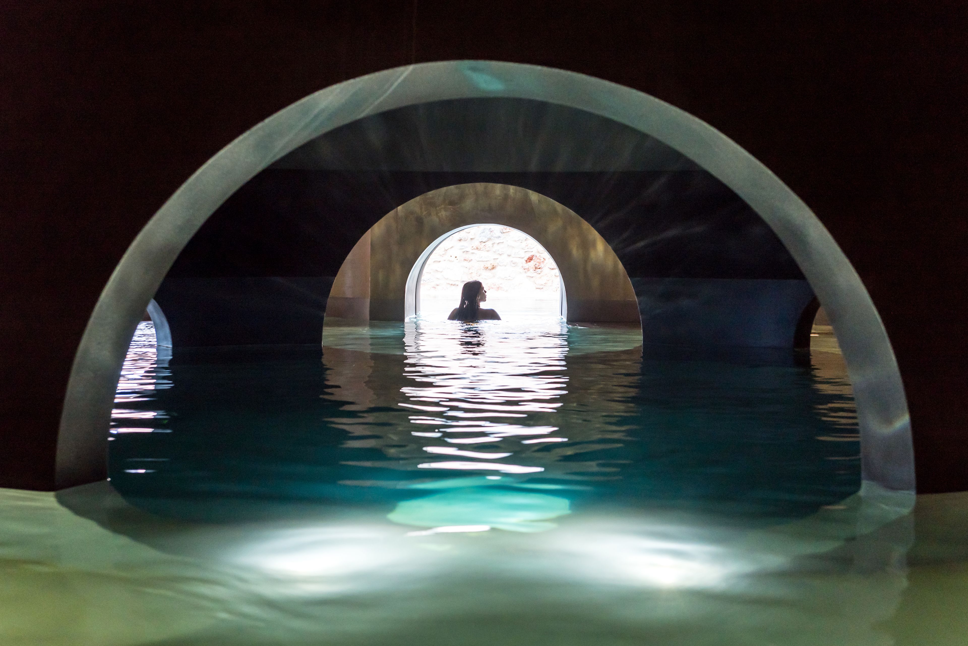 A person in a swimming pool with an arched structure above.
