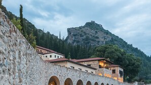 Ein Gebäude aus Stein mit mehreren Bögen und einem Berg im Hintergrund.