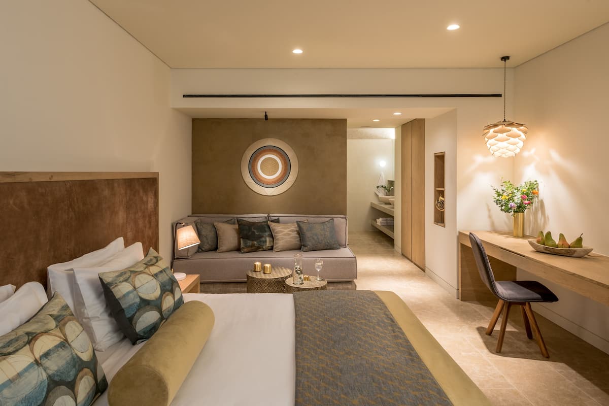 Une chambre d’hôtel moderne équipée d’un grand lit, d’un canapé, d’un bureau et d’un coin repas.