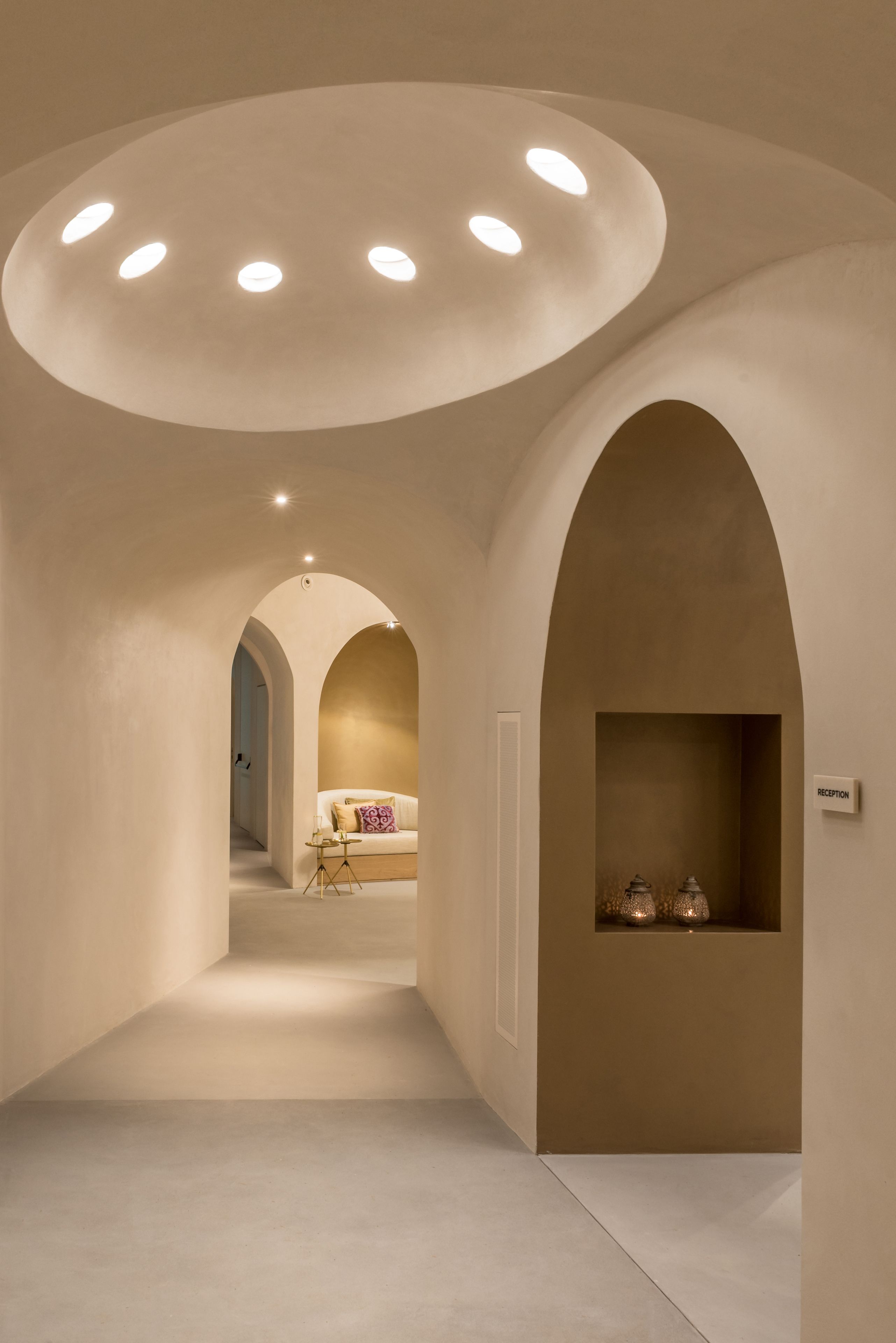 A hallway with a reception desk, a sofa, and a decorative shelf with two lanterns.