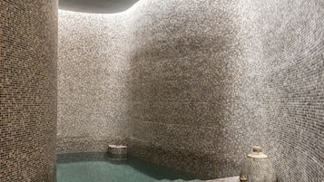 Un baño moderno con paredes de mosaicos y una fuente central de agua.
